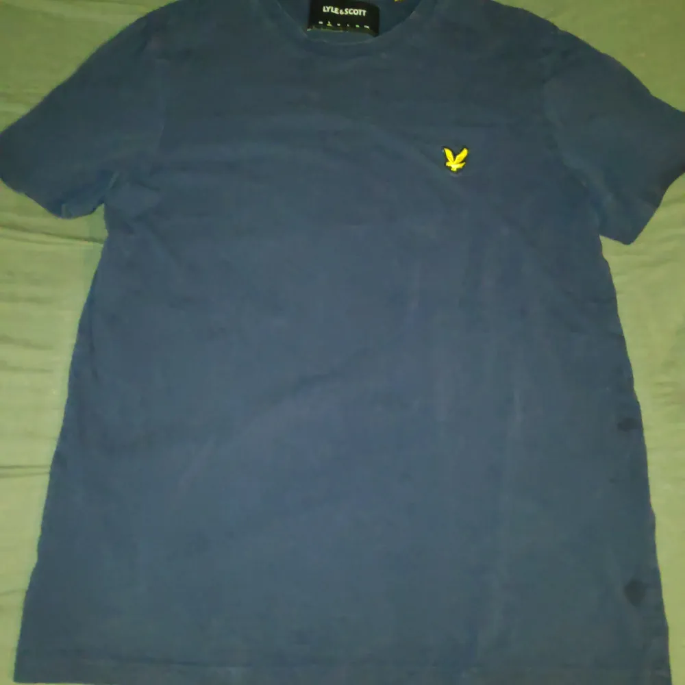 Säljer en blå t-shirt från Lyle & Scott med ett broderat logga på bröstet. Tillverkad i 100% bomull. Perfekt för en avslappnad stil.. T-paidat.
