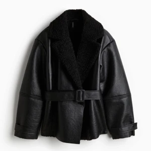 Svart skinnjacka med bälte - Snygg skinnjacka med en mjuk, fluffig krage och bälte i midjan, den virala jackan från H&M. Helt oanvänd med lappar på. 