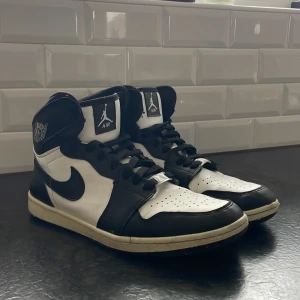 Svarta och vita Nike Air Jordans 1 - Riktigt snygga Nike Air Jordans 1 i svart och vitt med klassisk hög design. Skorna har snörning och den ikoniska Nike-loggan på sidan. Nypris 1300kr, skicket ligger på 7/10 lite söndriga inuti skon men de väldigt lite och syns och känns knappast, annars är dem som nya! Perfekta för dig som vill ha en stilren look med en sportig touch ✅