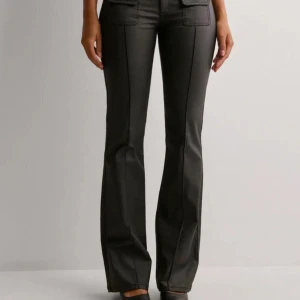 Svarta bootcut byxor med fickdetaljer - Snygga svarta bootcut byxor med hög midja och stilrena fickdetaljer. Byxorna har en smickrande passform och är perfekta för en trendig look. De är tillverkade i ett material som ger en elegant finish. Endast använda två gånger och helt slutsålda på nellys hemsida!💋