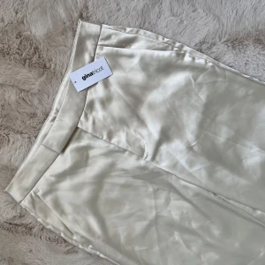 Kostymbyxor från Gina tricot  - Snygga kostymbyxor i satin/silke liknande material från Gina Tricot. De har en elegant wide fit och hög midja som ger en stilren look. Perfekta för en chic och modern stil. 