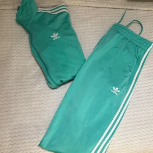 Turkosa mjukisbyxor från Adidas - Säljer detta fina turkosa adidas set pågrund av det ej längre kommer till användning. Köpt för 3 år sedan ungefär och byxor : xl passar L och Koftan : L passar M. Pris 500kr och köps i set! 