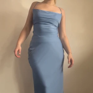 Ljusblå långklänning med öppen rygg - Oanvänd elegant blå långklänning med smala axelband och en vacker öppen rygg med snörning. Perfekt för speciella tillfällen 🩵 Passar även storlek small. Köpt vintage så vet inte märket