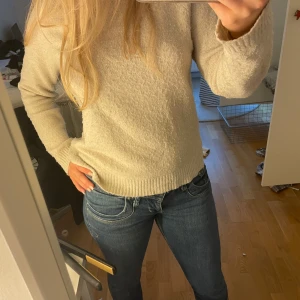 Beige stickad tröja - Säljer en mysig beige stickad tröja med långa ärmar. Tröjan har en croppad passform och ribbade muddar vid ärmslut och nederkant. Perfekt för en avslappnad stil. Hör av dig vid intresse! 😊