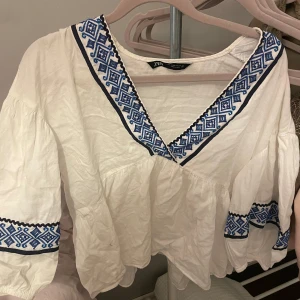Zara topp/blus - Säljer denna fina zara blus med söta detaljer. Köptes för 399 kr 2022 men endast använd fåtal gånger. Den är skrynklig pga den har legat i en låta länge utan att ha andvänts. Säljer för endast 200 kr men pris kan såklart diskuteras💘💘🫰🏼