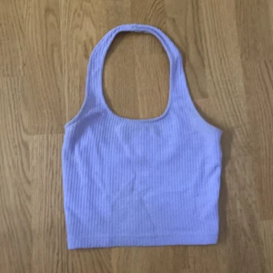 Lila ribbad linnetopp - Säljer en söt lila ribbad linnetopp med breda axelband. Perfekt för varma dagar och kan enkelt matchas med olika outfits. Toppen är i en mjuk och bekväm kvalitet.