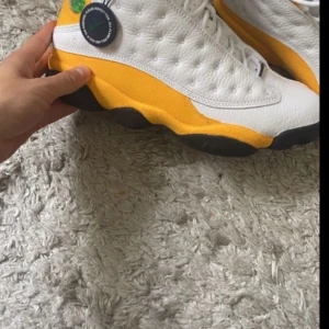  Jordans 13 - Snygga Nike Air Jordans i vitt med gula detaljer. Skorna har en klassisk design med snörning och en ikonisk logga på plösen. Perfekta för dig som vill ha en stilren och sportig look. Helt oanvända bara testade köpt för 4000 typ 