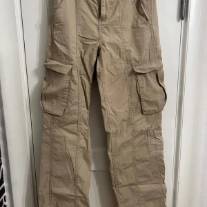 Beige cargobyxor - Snygga beige cargobyxor med flera praktiska fickor och en avslappnad passform. Perfekta för en casual look med en t-shirt eller hoodie. Byxorna har elastisk midja för extra komfort.