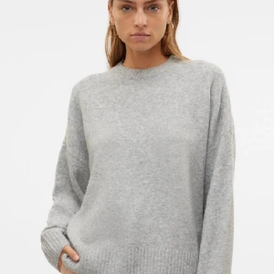 Grå stickad tröja - Säljer en mysig grå stickad tröja med rund hals och långa ärmar. Perfekt för kyliga dagar och enkel att matcha med olika outfits. Tröjan har ribbstickade muddar vid ärmslut och nederkant.