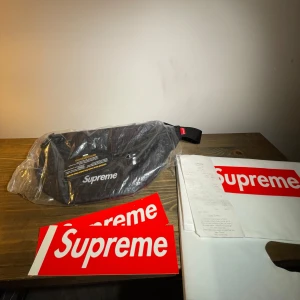 Supreme Waist Bag - Helt oanvänd supreme waistbag i svart. Fortfarande kvar i plastförpackningen. Kvitto från butiken i London medkommer samt originalpåse och klistermärken. Lägger något extra klistermärke vid smidig affär. Kom med bud!