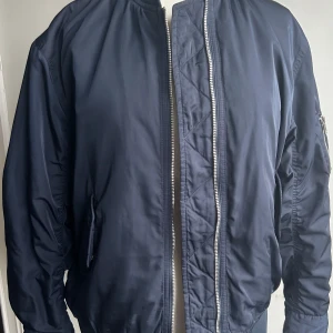 Mörkblå bomberjacka från Filippa K - Säljer en snygg mörkblå bomberjacka från Filippa K i storlek XS. Jackan har en klassisk bomberstil med dragkedja framtill och en praktisk ficka med dragkedja på ärmen. Perfekt för höst och vår!