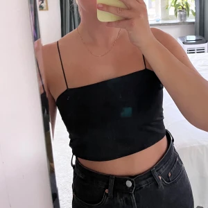 Topp med knytning i ryggen - Svart topp med knytning i ryggen från Zara. Bra skick, det är ingen fläck på framsidan utan det är ljuset som reflekteras.