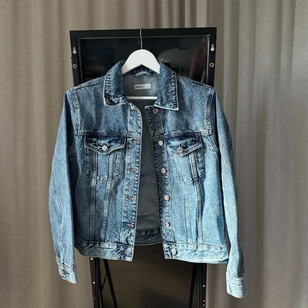 Säljer en snygg jeansjacka med markerade axlar från Gina Tricot i storlek M. Jackan är i klassisk blå denim med knappar framtill och två bröstfickor. Perfekt för vår och höst, och den har en normal passform. Aldrig använd, helt som i nyskick!. Jackor.