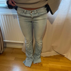 Ljusblå bootcut jeans - Säljer ett par ljusblå bootcut jeans i snygg och trendig stil. De är lågmidjade och har en klassisk femficksdesign med knappar och dragkedja framtill. Perfekta för en avslappnad vardagslook! från diesel. midjemått ca 82 och innerbens längd ca 85