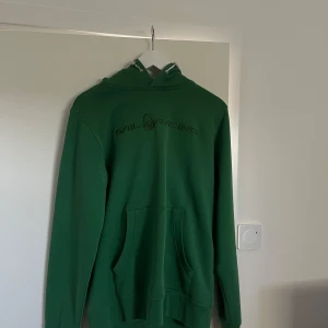 Grön hoodie från Sail Racing - Säljer en snygg grön hoodie från Sail Racing. Den har en stor ficka fram och en bekväm huva. Perfekt för kyliga dagar och har en stilren logga på bröstet. Passar både till vardags och för lite mer avslappnade tillfällen.