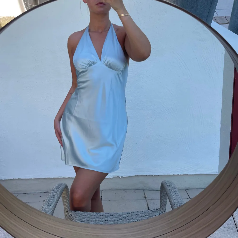 Säljer en superfin ljusblå klänning i satin. Den har en snygg halterneck-design som ger en elegant look. Perfekt för sommarens fester eller en dag på stan. Klänningen är kort och har en smickrande passform. Liten i storleken 🩵. Mekot.