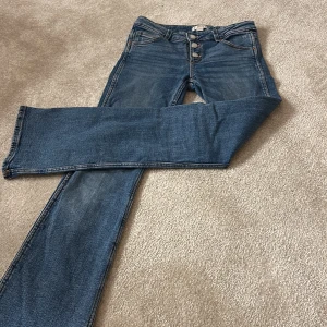 Blå jeans från Gina Tricot - Säljer ett par snygga blå jeans från Gina Tricot. De har en klassisk vintage design och är lågmidjade med knappar framtill. Perfekta för både vardag och festen 💞