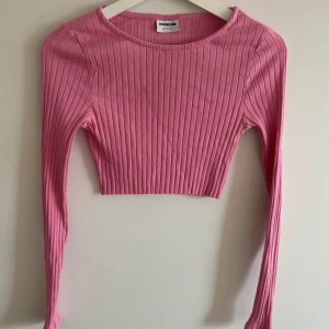 Rosa ribbad croppad topp från Noisy May - Säljer en superfin rosa ribbad topp från Noisy May. Den är croppad och har långa ärmar, perfekt för både vardag och fest. Toppen är i ett mjukt och stretchigt material som sitter snyggt på kroppen. Passar perfekt till ett par höga jeans eller kjol!
