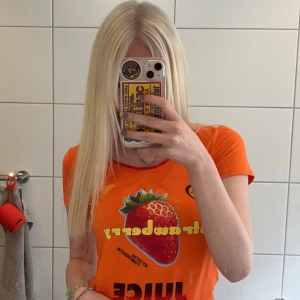 Orange t-shirt med jordgubbstryck - Säljer en cool orange t-shirt från Dolce & Gabbana Underwear med ett stort jordgubbstryck och texten 'Juice' på framsidan. Den är kortärmad och har en normal passform. Perfekt för sommardagar! 🍓🧡