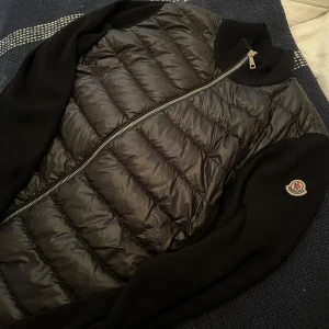 Moncler Cardigan - Hejsan! Säljer min Moncler cardigan då den desvärre inte kommer till användning längre.  Kvitto finns tyvärr inte, då jag tappade bort de under min flytt.  Köpt på NK Göteborg April 2023 för runt 8000kr. Garanterar äkta. Har bildbevis när jag köpte j