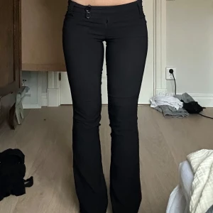 Svarta lågmidjade kostymbyxor - Snygga svarta kostymbyxor med låg midja och två knappar framtill.