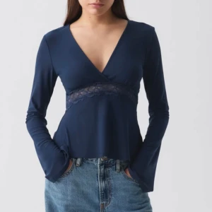 Mörkblå topp med spetsdetalj - Snygg mörkblå topp med v-ringning och spetsdetalj under bysten. Storlek S från Gina tricot. Toppen har aldrig använts och har kvar prislapp.