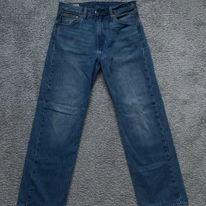 Blå Levis jeans - Säljer ett par klassiska blå Levis jeans med rak passform. De har en hög midja och är tillverkade i slitstarkt denim. Perfekta för en avslappnad stil.