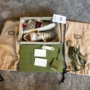 Gucci sneakers med monogrammönster - Snygga Gucci sneakers med klassiskt monogrammönster i beige och brunt. Skorna är i 9/10 skick, sulan är väldigt ren och monogram mönstret är som nytt! Skorna är köpta på Vestiaire Collective och legitcheckade hos de (finns screenshot). Så 100% äkta, kommer med dustbags för båda skorna, extra skosnören, tags och boxen som skickades av Vestiaire Collective! Nypris 8700kr! (Säljs för de var för stora!)