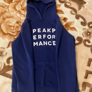 Blå hoodie från Peak Performance - Säljer en snygg blå hoodie från Peak Performance. Den har en klassisk känguruficka och en bekväm huva. Storleken är 170 men passar nog dig om du har storlek S och XS.