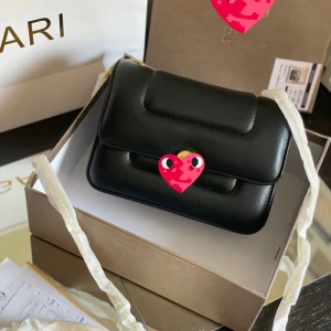 Svart axelväska med kedja - Elegant svart axelväska med guldfärgad kedja och stilren design. Väskan har en quiltad look och är perfekt för att ge en touch av lyx till din outfit.