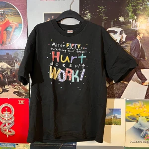 Svart vintage t-shirt med färgglad text - Säljer en svart t-shirt från Alstyle Apparel & Activewear med färgglad text på framsidan. Texten har en humoristisk ton och är tryckt i olika färger som röd, gul, blå och lila. Perfekt för en avslappnad stil!