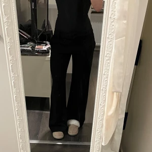 Svarta byxor från BCX - Snygga svarta kostymbyxor från BCX i en skön blandning av polyester, spandex och rayon. Byxorna har en hög midja och en bootcut-stil som ger en elegant siluett. Perfekta för en stilren look. Lågmidjade