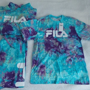 Nytt set från FILA 3 plagg, hoddie/byxor/t-shirt - Säljer ett nytt färgglatt set från FILA med hoddie, t-shirt och byxor i tie-dye mönster.   Säljer alla 3 plaggen som ett paket för halva inköpspriset. Köpte det för ca 2000kr. Säljer det för 750r så passa på att göra ett fynd nu. Från rök och djurfritt hem.