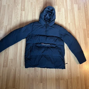 Svart pufferjacka från Champion - Säljer en svart pufferjacka från Champion med huva och dragkedja. Jackan har en stor ficka framtill med Champion-logga. Perfekt för kalla dagar. Storlek X-large