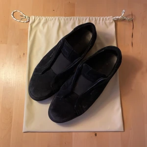 Axel Arigato Clean 360 Laceless - Snygga helsvarta sneakers från Axel Arigato i mocka. Pris diskuterbart. Säljer dessa då storleken inte passar mig längre, annars inget fel på dem. Bra skick 8/10. Bara använda i någon månad i sommras så dem hann inte slitas så mycket. Storlek 43, men passar även 44. Dustbag medkommer.