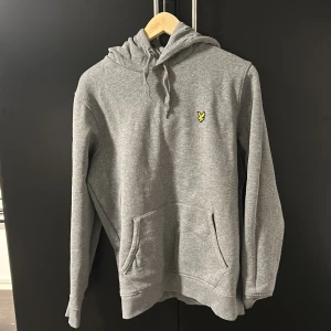 Grå hoodie från Lyle & Scott - Säljer en stilren grå hoodie från Lyle & Scott med deras ikoniska logga på bröstet. 