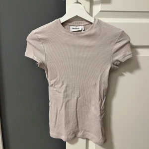 Beige ribbad t-shirt  - Säljer en stilren beige ribbad t-shirt från Weekday. Den har en klassisk rund hals och korta ärmar.