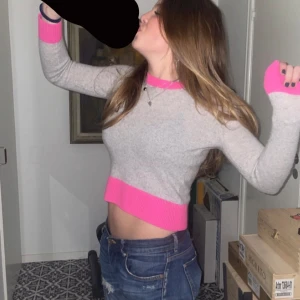 Grå och rosa tröja från From Future - Snygg grå 100% kashmir tröja med rosa detaljer från From Future. Helt nyskick använd max fem gånger! Tröjan har en lite tajtare passform (på mig) med långa ärmar, kan användas både till festligheter och skolan. (Den är inte så kort bara jag som sträcker mig på ett konstigt sätt)❤️🥰