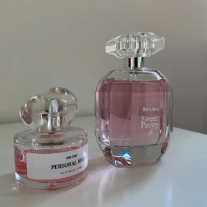 Parfymer Personal Muse och Bershka Sweet Peony - Två eleganta parfymer: Personal Muse i en rund flaska med en unik, vriden kork och Bershka Sweet Peony i en större, facetterad flaska. Båda har en ljusrosa vätska som ger en feminin och fräsch känsla.