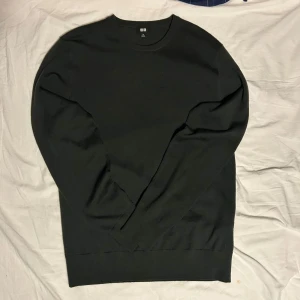 Mörkgrön tröja från Uniqlo - Säljer en stilren mörkgrön tröja från Uniqlo. Tröjan har en klassisk rund hals och är tillverkad i ett mjukt material som passar perfekt för kyligare dagar.  Den har en liten defekt vid bröstet men som typ inte syns 