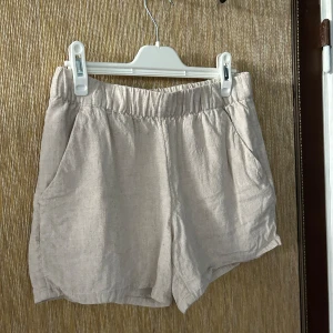 Beige shorts i linne - Säljer ett par superbekväma beige shorts i linne. De har en elastisk midja för en skön passform och två praktiska sidofickor. Perfekta för varma sommardagar eller en avslappnad vårlook. 🏖️