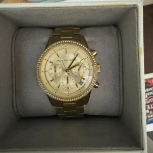 guldig michael kors klocka  - klockan behöver ett batteribyte, har tappat färg på baksidan 