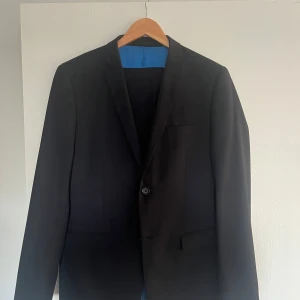 Kostym- kavaj + kostymbyxor - Mörkblå kostym från Lindbergh. Mycket fint skick då den är använd enstaka gånger. Storleken motsvarar ~S/ mindre M. 