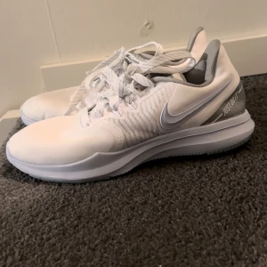 Nike träningsskor  - Vita inomhus-träningsskor från Nike. Passar perfekt till gym, kanske även tennis eller padel. Ljusblå och grå detaljer. Storlek 37,5 men känns som 37.  Fläck framtill på vänsterskon (se bild).  Fler bilder/filmer finns 