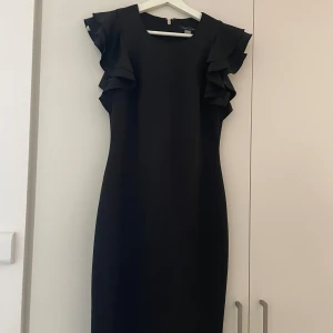 Svart ruffleklänning från Tommy Hilfiger  - Säljer denna fina klänning från Tommy Hilfiger, inköpt i New York för två år sedan men knappt använd. Strl 4 vilket jag tror motsvarar s, men funkar lika bra på mig som är strl m, allt beror på hur man vill att den ska sitta. Otroligt fint skick🤩