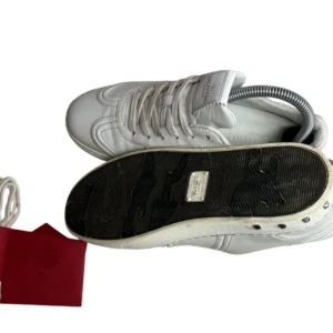 Vita sneakers från Valentino - Snygga vita sneakers från Valentino med klassisk design och snörning. Skorna har en stilren look med diskreta detaljer och är perfekta för en trendig stil. 2 spikar borta men annars jätte fint skick 