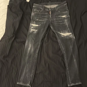 Svarta jeans med slitningar från Dsquared2 - Snygga svarta jeans från Dsquared2 med coola slitningar och en modern look. De har en dragkedja och knapp framtill samt klassiska fem fickor. Perfekta för en trendig stil.