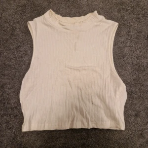 Vit ribbad  topp - Säljer en stilren vit  topp utan ärmar. Perfekt för lager-på-lager eller sommartid. Enkel och mångsidig design.