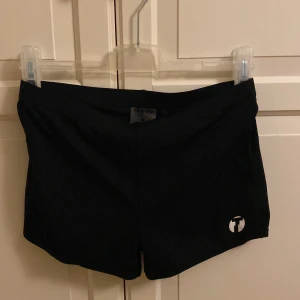 Svarta shorts från Trimtex - Snygga svarta shorts från Trimtex med en enkel design och en liten logotyp på benet. Perfekta för en sportig look eller avslappnad stil. De är tillverkade i ett bekvämt material som passar bra för olika aktiviteter. I fint skick och storleken är M.