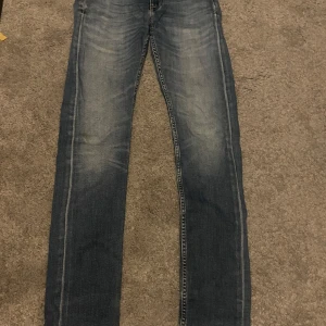 Blå slim jeans från Tiger of Sweden - Snygga blå jeans från Tiger of Sweden med klassisk femficksdesign och ljusa tvättade detaljer. Perfekta för en avslappnad stil. Märkeslapp i läder baktill ger en extra touch.